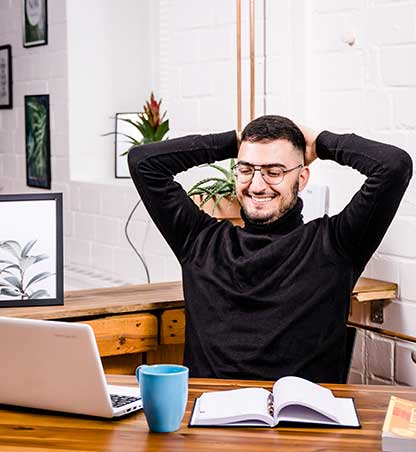 Mann sitzt entspannt am Schreibtisch und informiert sich über die Miete des Coworking Lofts Kreuzau.