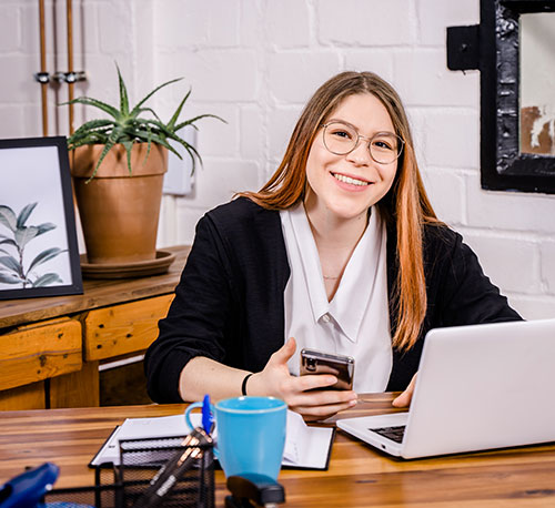 Ansprechpartnerin vom Coworking Space in Kreuzau sitzt an einem Schreibtisch.